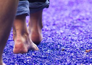 Menschen laufen barfuß auf einem lila/blauen Weg