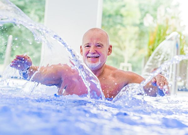 Ein Mann steht in einem Schwimmbecken und wirbelt Wasser mit den Händen auf