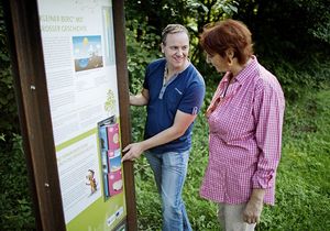 Ein Mann und eine Frau stehen vor einer Informationstafel im Grünen