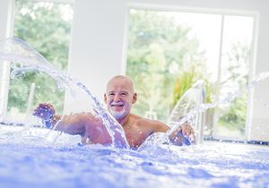 Ein Mann steht in einem Schwimmbecken und wirbelt Wasser mit den Händen auf