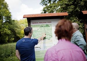 Zwei Männer und eine Frau schauen sich eine Wanderkarte im Grünen an
