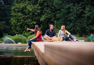 Zwei Frauen und ein Mann machen auf einem Steg am Gewässer eine Pause